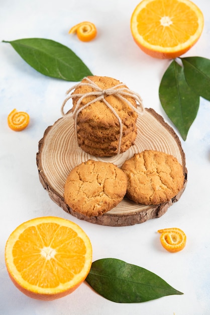 Photo gratuite photo verticale de biscuits faits maison sur planche de bois et oranges juteuses fraîches.