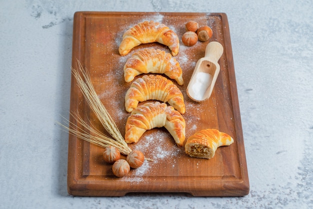 Photo verticale de croissants frais faits maison sur planche de bois sur une surface grise.