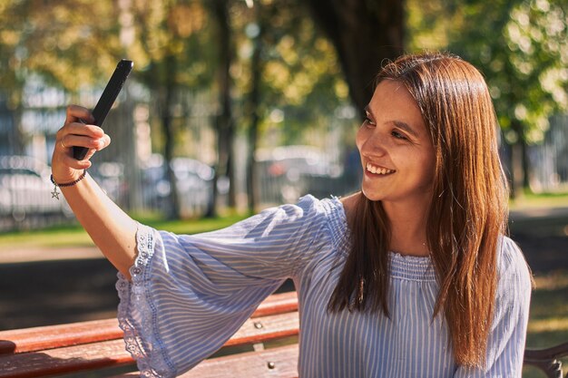 Photo verticale d'une fille dans une chemise bleue prenant un selfie