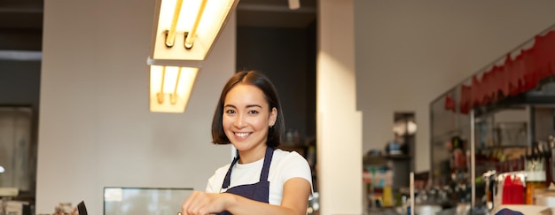 Photo gratuite une photo verticale d'une fille souriante travaillant en tant que barista se prépare à verser sur le filtre de café.