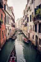 Photo gratuite photo verticale de gondoles sur le grand canal entre les bâtiments colorés à venise, italie