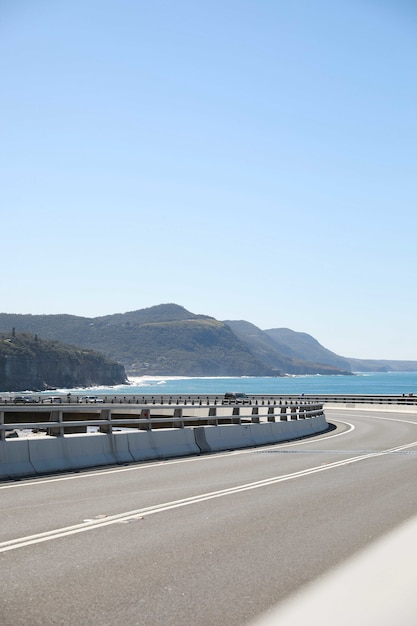 Photo verticale d'une longue route sinueuse contre les montagnes et l'océan