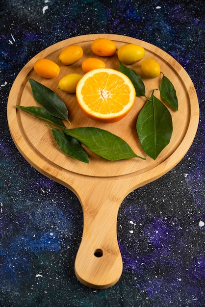 Photo verticale d'orange à moitié coupée avec des feuilles et des kumquats.