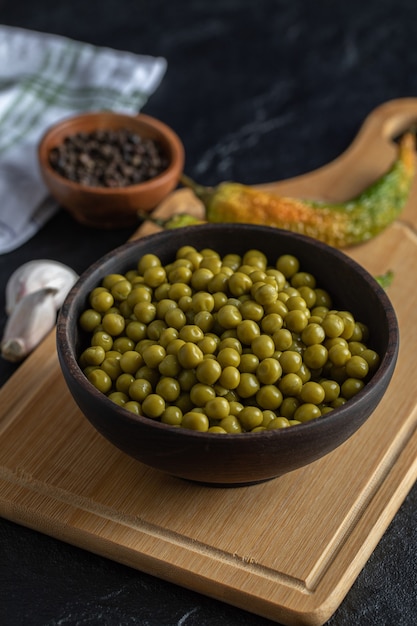 Photo gratuite photo verticale de pois verts marinés sur planche de bois.