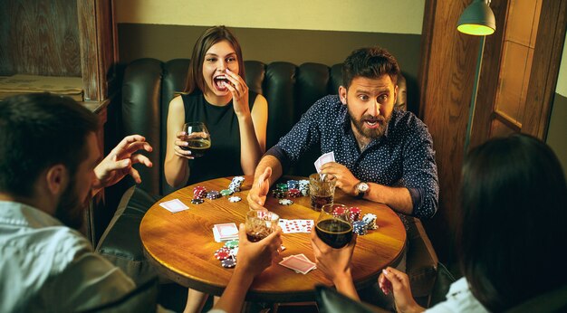 Photo vue latérale d'amis assis à table en bois. Amis s'amusant tout en jouant au jeu de société.