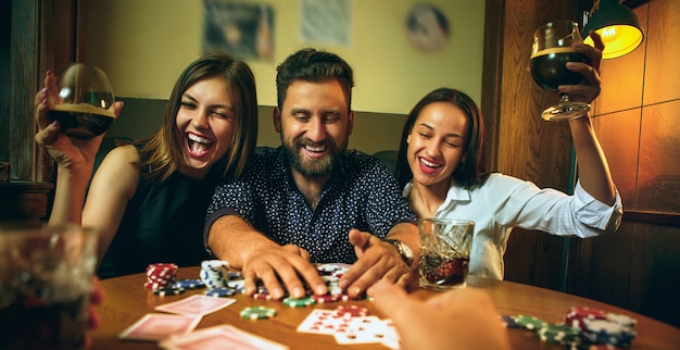 Photo vue latérale d'amis assis à table en bois. Amis s'amusant tout en jouant au jeu de société.