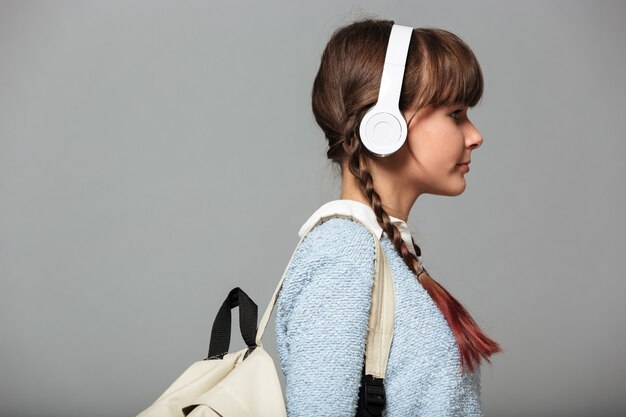 Photo vue latérale d'une fille qui écoute de la musique avec des écouteurs