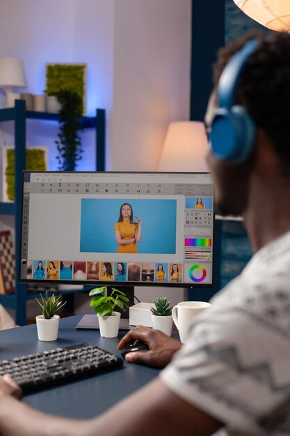 Photographe d'artiste afro-américain avec casque retouchant des images de créateurs à l'aide d'un logiciel de post-production numérique. Jeune éditeur d'illustrateurs éditant des photographies créatives travaillant à distance depuis chez soi