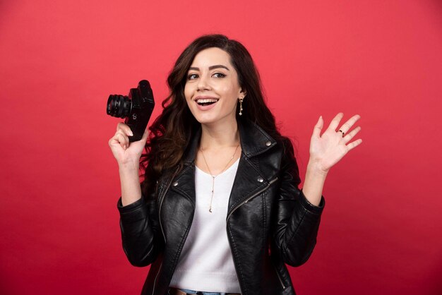 Photographe de belle femme tenant un appareil photo sur fond rouge. photo de haute qualité