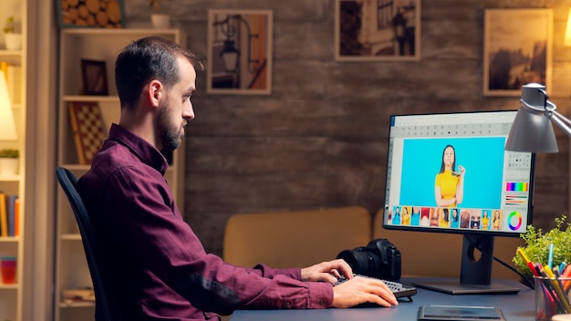 Photographe créatif utilisant un programme de retouche numérique. Retouche de fin de soirée. Caméra sur bureau.