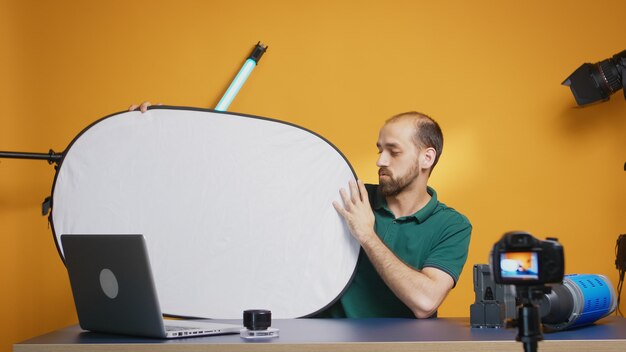 Photographe enregistrant un vlog sur le réflecteur de lumière blanche en studio. Technologie d'équipement vidéo et photo de studio professionnel pour le travail, star des médias sociaux et influenceur de studio photo