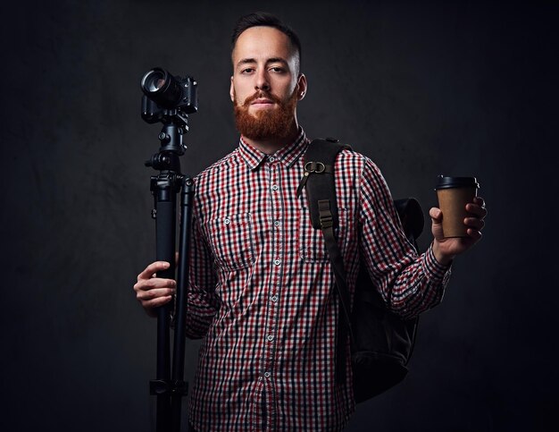 Photographe indépendant barbu rousse avec trépied et sac à dos.