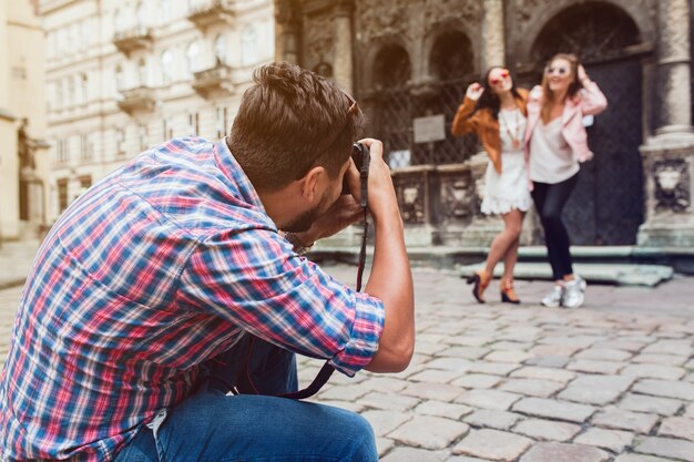 Photographe jeune homme prenant des photos, prenant des photos avec un appareil photo numérique à ses amis