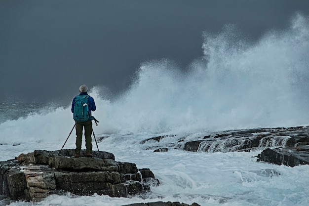 Photo gratuite photographe sur les rochers en mer orageuse