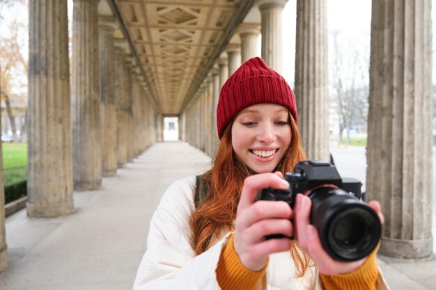 Une photographe touristique souriante prend une photo pendant son voyage tient un appareil photo professionnel et fait une photo