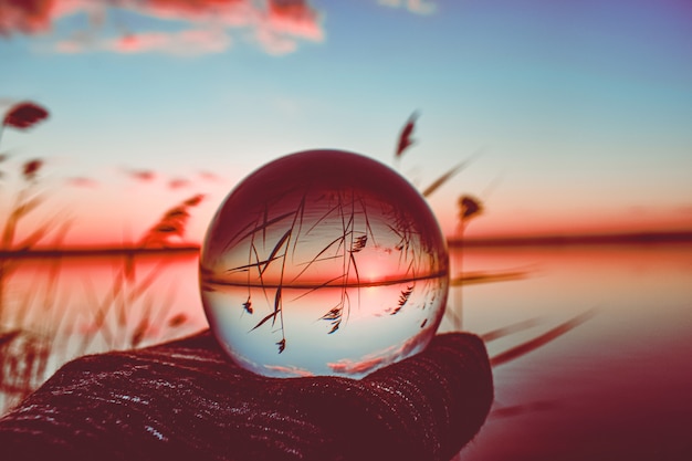 Photographie de boule de lentille de cristal créative d'un lac avec une grande verdure autour