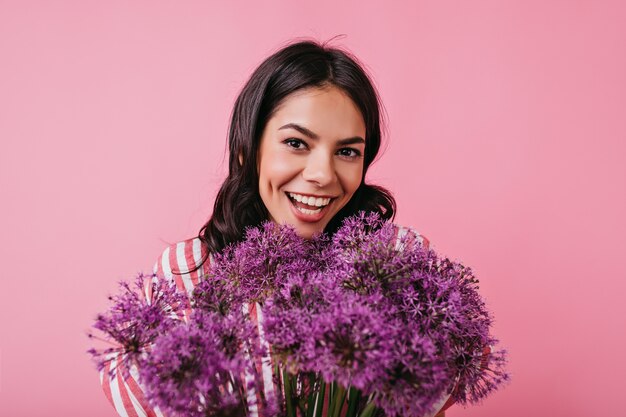 Photos. Jeune fille avec gros bouquet de lilas dans ses mains posant pour portrait.