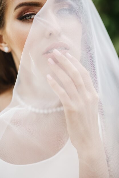 Photos de la mariée magnifique posant sous le voile à l&#39;extérieur