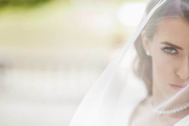 Photos de la mariée magnifique posant sous le voile à l&#39;extérieur