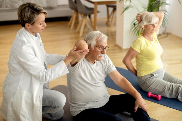 Physiothérapeute aidant un couple d'âge mûr à faire des exercices à la maison