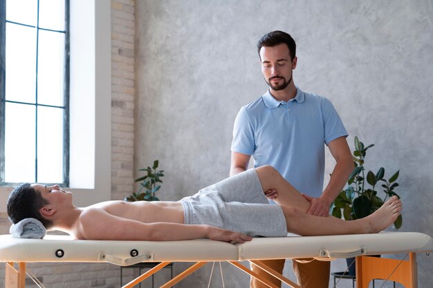 Physiothérapeute de coup moyen vérifiant la jambe