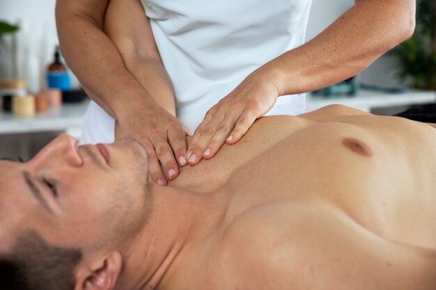 Physiothérapeute effectuant un massage thérapeutique sur un client masculin