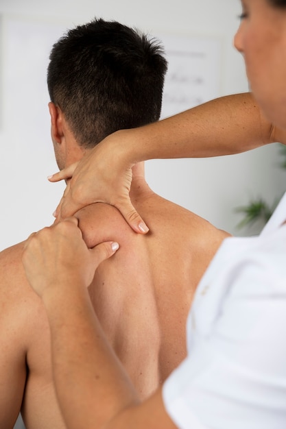 Photo gratuite physiothérapeute effectuant un massage thérapeutique sur un client masculin