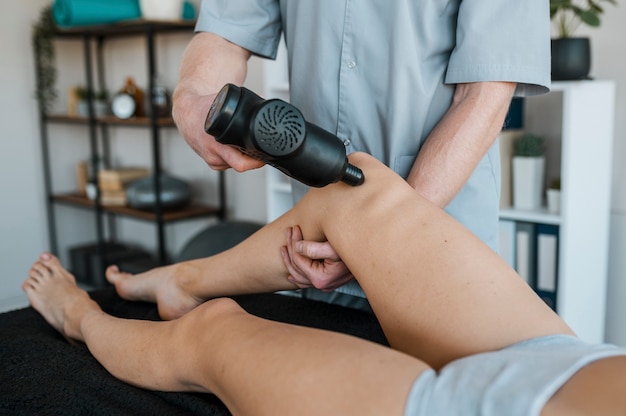 Physiothérapeute masculin à l'aide de l'équipement de patiente au cours d'une séance de physiothérapie