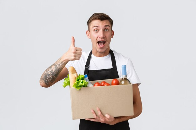 Épicerie au détail et concept de livraison beau courrier en tablier noir remettant la boîte avec g...