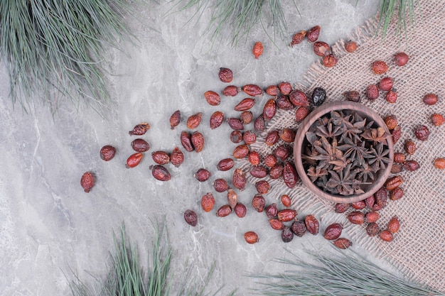 Épices d'anis dans une tasse en bois avec des hanches