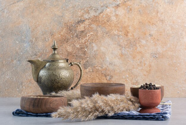 Épices dans des tasses rustiques en bois avec une théière de côté.