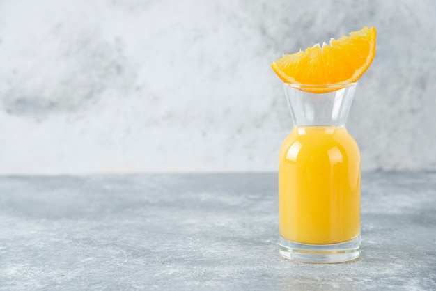 Pichet en verre de jus avec tranche de fruit orange.