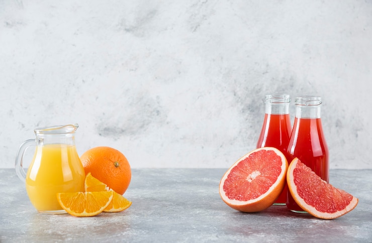 Photo gratuit pichets en verre de jus de pamplemousse avec des tranches de fruits orange.