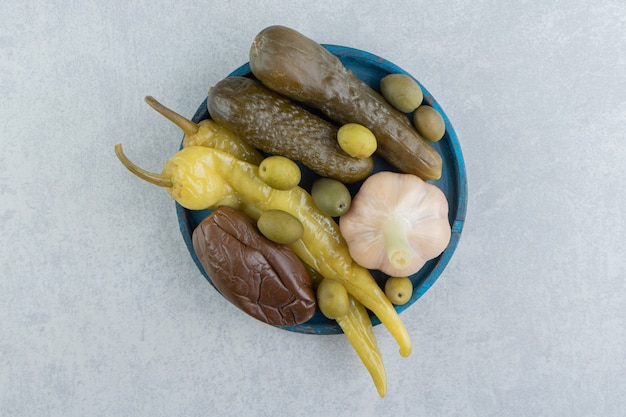 Pickles piments forts, olives, concombres et aubergines sur la plaque en bois sur la surface en marbre