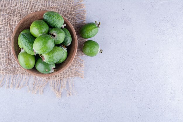 Pièce de tissu sous un petit bol de feijoas sur fond de marbre. photo de haute qualité