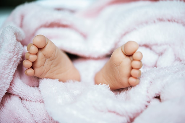 Pieds de bébé nouveau-né sur une couverture blanche