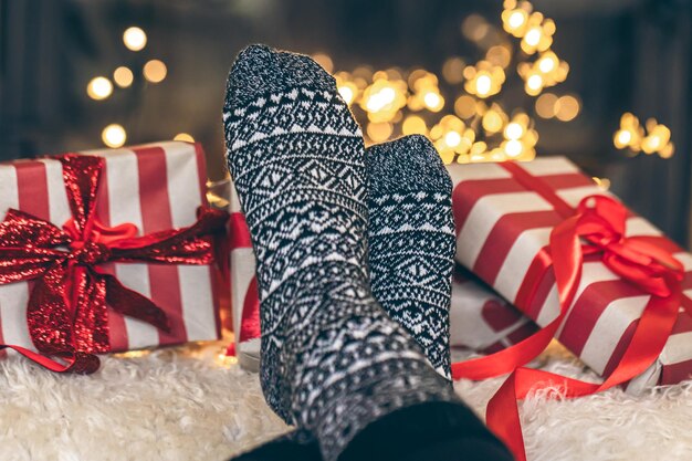 Photo gratuite les pieds dans des chaussettes de noël et des boîtes de cadeaux devant la cheminée de près