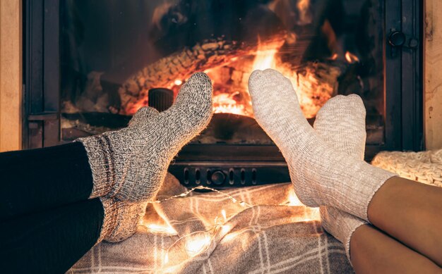 Les pieds des femmes dans des chaussettes chaudes se réchauffent au coin du feu