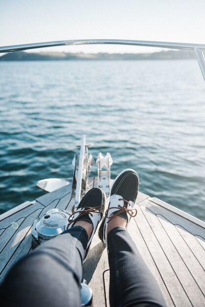 Les pieds de la personne sur le bateau naviguant sur la mer pendant la journée