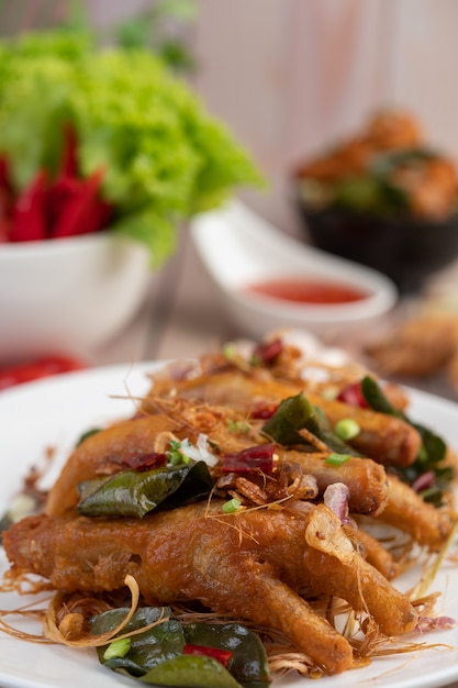 Pieds de poulet frit aux herbes sur une plaque blanche et trempette.