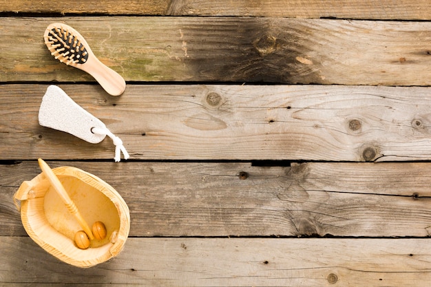 Photo gratuite pierre ponce, brosse à cheveux et masseurs de rouleaux en bois sur la vieille table