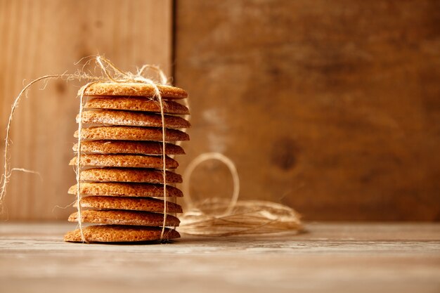 Pile de biscuits attachés avec une corde artisanale sur une table en bois. Idée de cadeau de vacances.