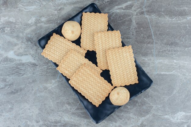 Pile de biscuits faits maison sur une plaque en céramique noire.