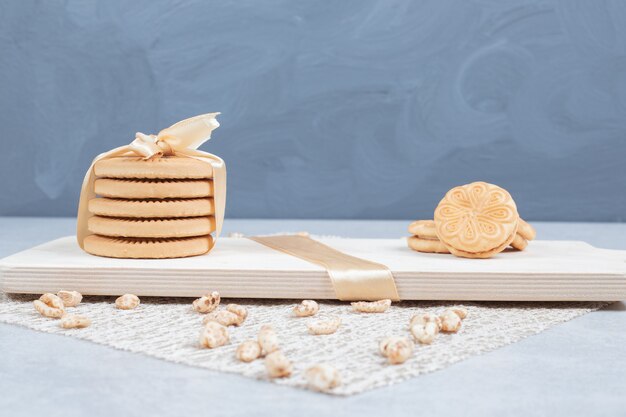 Pile de biscuits festifs et d'arachides sur planche de bois.