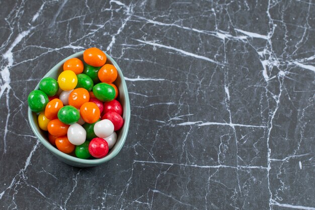 Photo gratuite pile de bonbons colorés dans un bol bleu.