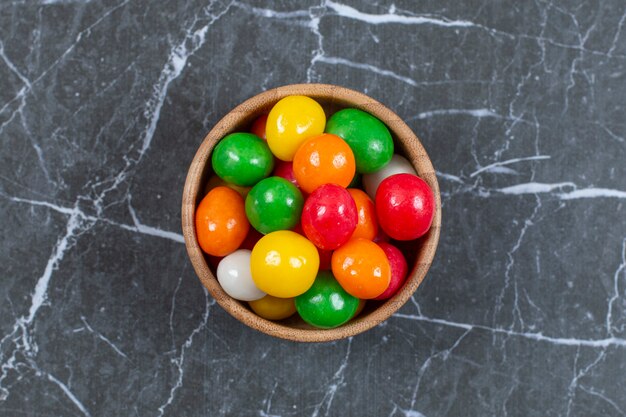 Pile de bonbons colorés dans un bol en bois.