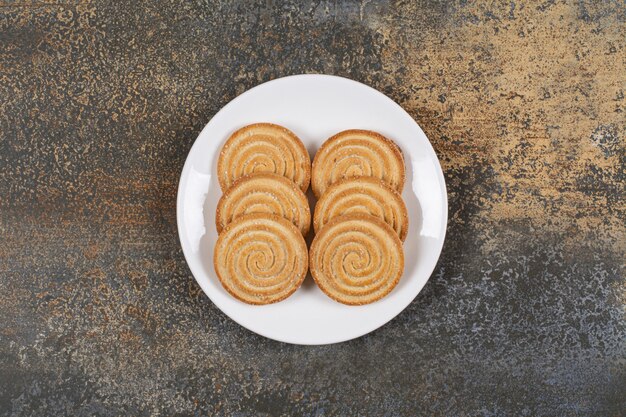 Pile de délicieux biscuits ronds sur plaque blanche.