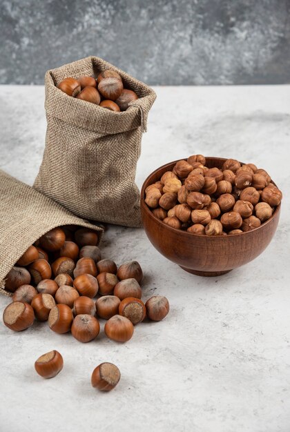 Pile d'écalées biologiques et de noyaux de noisettes en toile de jute et dans un bol.