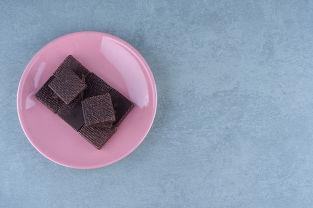 Pile de gaufrettes au chocolat frais sur plaque rose.