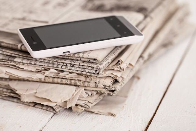 Pile de journaux avec smartphone dessus